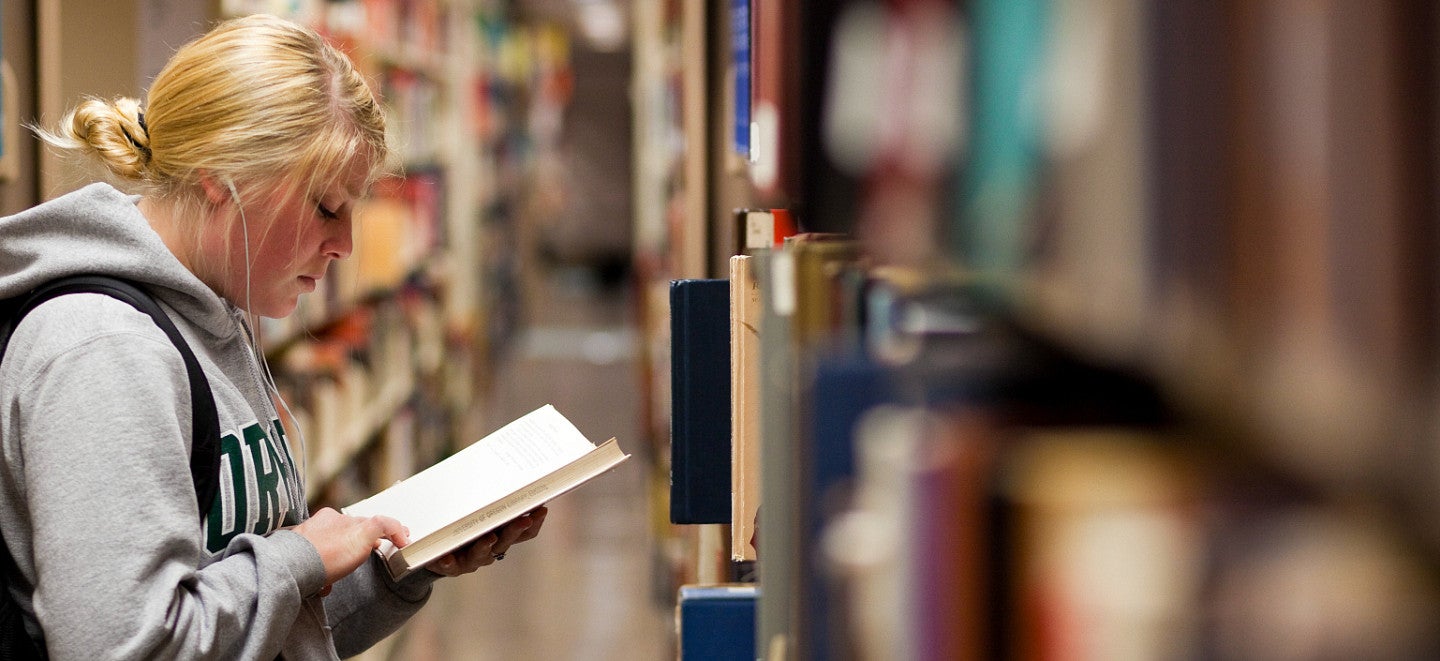 student reading a book in a library