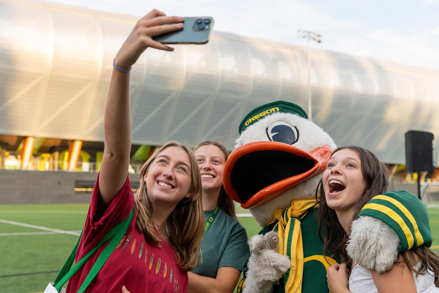 three students taking a photo with the duck