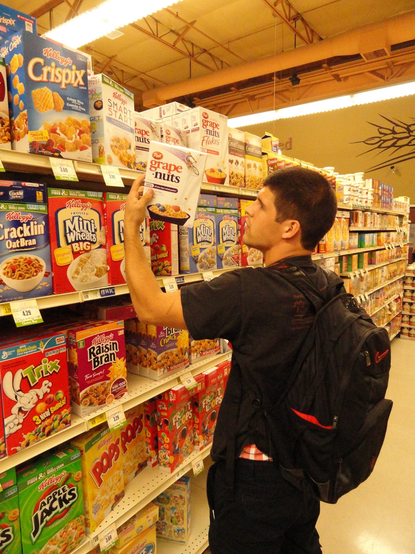 Photo of student in a grocery store looking at nutrition facts on a box.