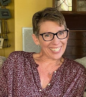 Faculty Jamie Bufalino, a white woman with short hair, wearing a red and white shirt and black glasses, smiling toward the camera.