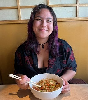 FIG Assistant Maya smiling with a bowl of Ramen