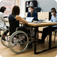 Four people, one in a wheelchair, sitting around a table working